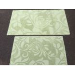 A graduated pair of wool & cotton rugs, woven in a pale green floral scrolled design. (2)