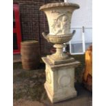 A massive composition stone garden urn on stand