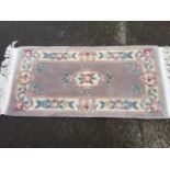 A Chinese thick pile rug, woven with pastel floral medallion & border on puce ground.