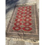 A bokarra rug woven with fourteen octagonal hooked red panels on grey ground