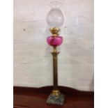 A Victorian brass oil lamp with classical fluted column having scrolled capitals with ruby glass
