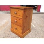 A dwarf pine chest with three knobbed drawers raised on a plinth.