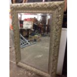 A large bevelled mirror in decorative leaf moulded gilt frame.