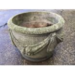 A circular composition stone garden pot moulded with swags.