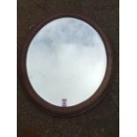 An oval oak framed mirror, with bevelled plate in bead moulded frame.