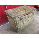 A large cane basket with hinged lid, raised on two batons with handles to ends.