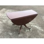 A circular mahogany drop-leaf table, the top with reeded edge supported on a column with