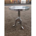 A circular polished aluminium occasional table