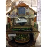 A Flying Scotsman themed cuckoo clock, decorated as a station with locomotives and rail, packaged