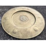 A circular embossed brass tray or plaque