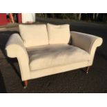 A small contemporary sofa with loose cushions, raised on turned legs with brass casters.