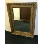 A rectangular hall mirror in a heavy gilt frame with foliate decoration.