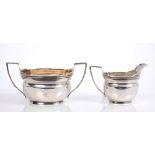 George III silver cream jug of waisted oval form, with angular handle and engraved armorial crest,