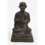 Thai bronze devotional figure modelled as a seated monk, on inscribed plinth base,