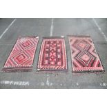 Three Kelim rugs, typical geometric ornament in muted red tones,