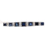 Sapphire and diamond bar brooch with a graduated line of seven step cut blue sapphires weighing