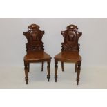 Pair of early Victorian mahogany hall chairs, each with relief carved cartouche,