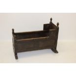 17th century oak cradle of panelled construction with turned finial on rockers