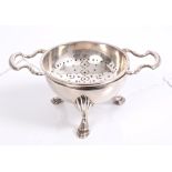Contemporary silver tea strainer with scroll handles and stand, on three hoof feet (London 1962),
