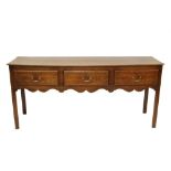 Mid-18th century oak dresser base with three drawers above undulating frieze on square supports,