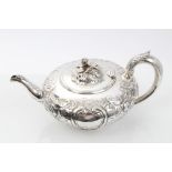 Victorian silver teapot of compressed form, with embossed scroll and floral decoration,