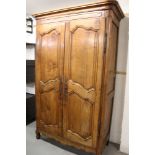 19th century French fruitwood armoire enclosed by a pair of shaped fielded panel doors,