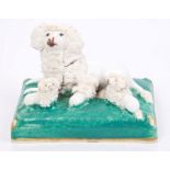 19th century Staffordshire porcelain group of a poodle with three puppies on a cushion,