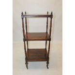 Regency rosewood whatnot with three rectangular tiers between turned supports on castors,