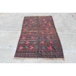 Eastern tribal rug, dark red and blue tones with geometric bands with tassel ends,