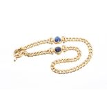 Yellow metal curb link necklace with two heart-shape lapis lazuli panels with bullet-shape