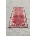 Persian rug, the narrow back red field with flower-head and geometric device, in multiple borders,