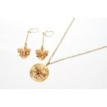 Yellow metal pendant on chain and matching earrings with stylised orchid design