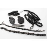 Group of jet and black bead necklaces - including large carved oval locket and a brooch