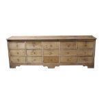 19th century pine dresser base with an arrangement of fifteen drawers with brass ring handles,