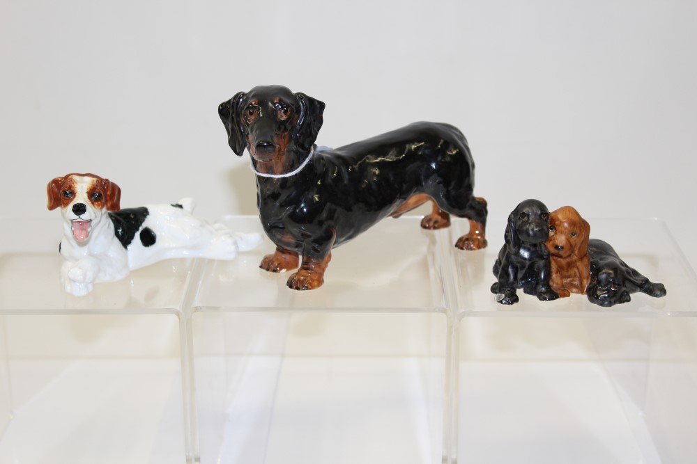 Two Royal Doulton dogs - HN1101 and HN1128 and a Royal Worcester group of three puppies