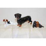 Two Royal Doulton dogs - HN1101 and HN1128 and a Royal Worcester group of three puppies