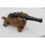 Decorative iron signalling cannon with lion mask to barrel, on wooden and brass carriage,