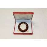 Le Must de Cartier gilt metal and red enamel oval photograph frame with easel back and cabochon