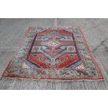 Persian carpet, the salmon-pink ground with angular geometric design with multiple meander borders,