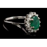 Emerald and diamond cluster ring, the oval mixed cut emerald measuring approximately 9.20mm x 6.