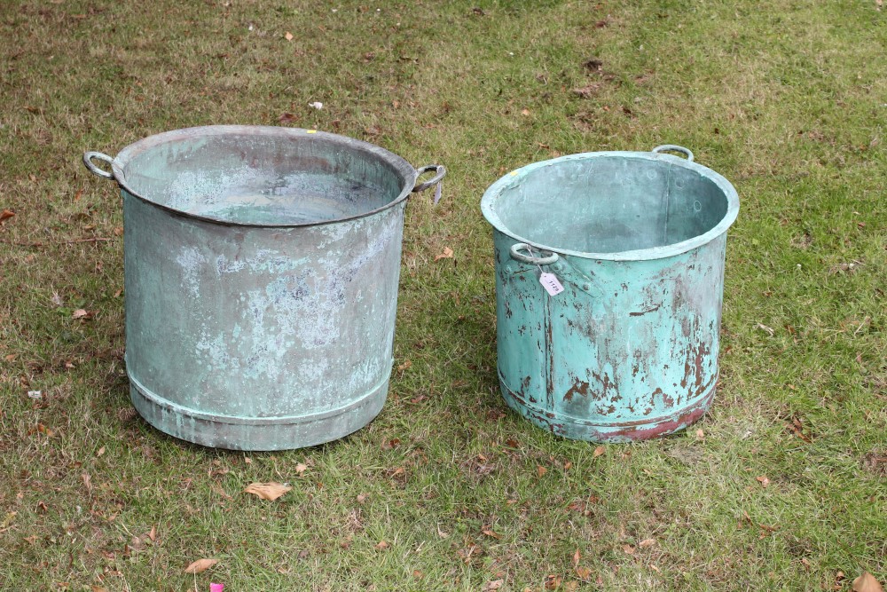 Two graduated copper vessels, each of riveted form, with everted rim and flanking handles,