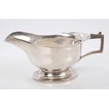 1930s silver-footed sauce boat with a wavy border and angular handles,