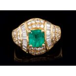 Emerald and diamond cocktail ring with a central rectangular step cut emerald flanked by two bands