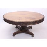 19th century Anglo-Indian carved teak dining table, the circular tilt-top with lotus carved edge,