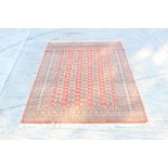 Good Bokhara style rug - having five rows of twenty quartered medallions on brick-red ground in