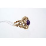 Unusual amethyst dress ring with a round cabochon amethyst in a yellow metal foliate mount.