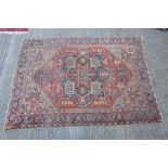 Good Heriz carpet - brick-red field with concentric angular serrated medallion and branchwork