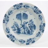 18th century English Delft plate painted in blue in the Chinese style, with a figure in a garden,