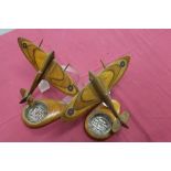 Pair of Second World War wooden models of Spitfire fighter aircrafts raised above ashtrays,