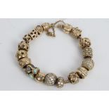 Pandora Moments bracelet with quantity of gold and yellow metal charms by various manufacturers